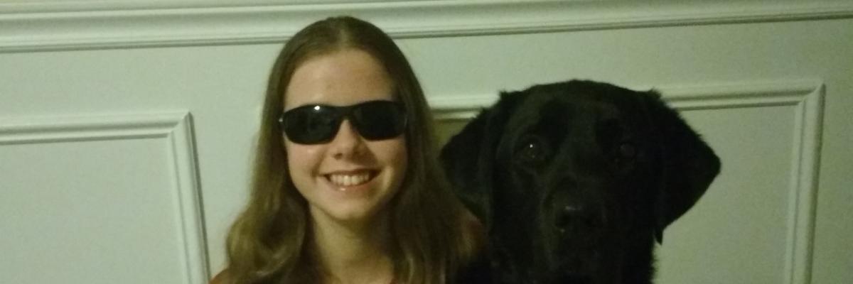  Adolescente ayant une perte de vision qui sourit en serrant son chien-guide contre elle. 