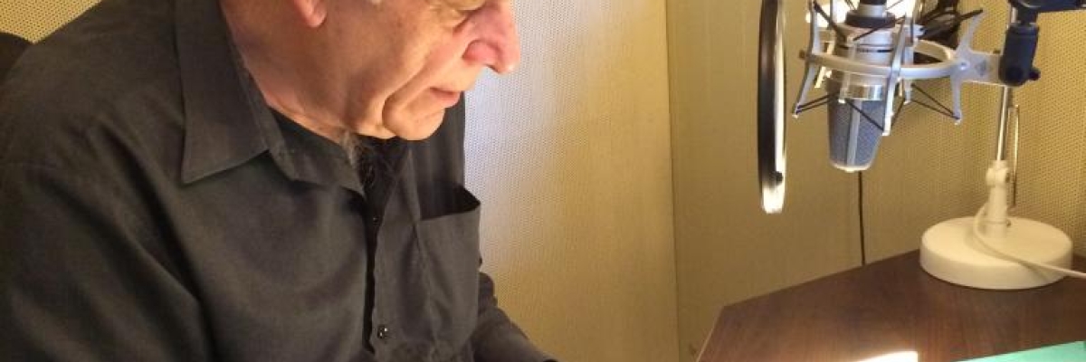 Pierre Germain reading a book in front of a mic