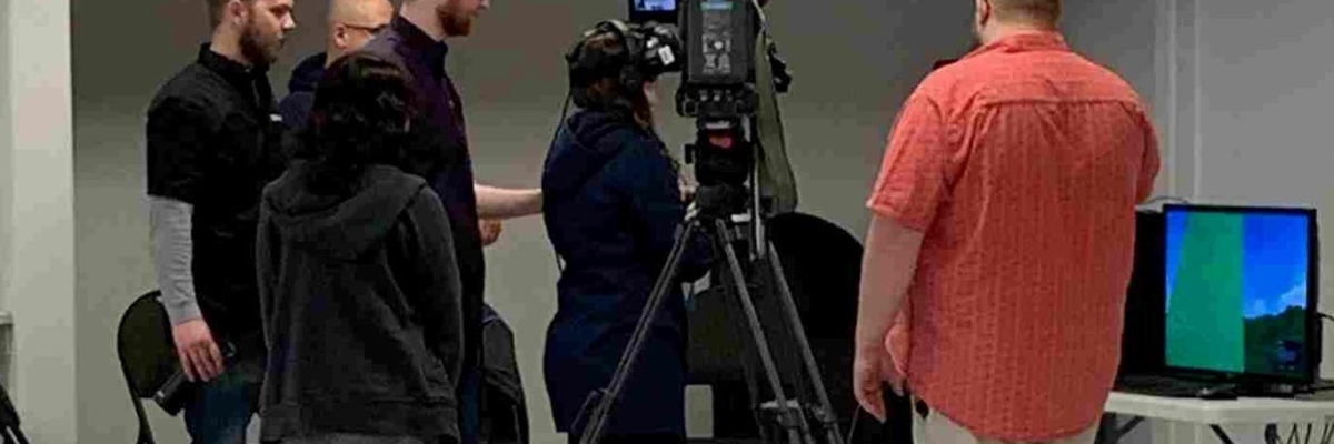 News camera films a youth with virtual reality goggles on