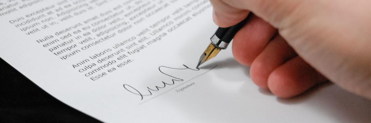 A hand signing a document.