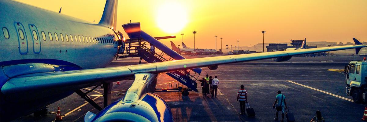 People boarding an airplane at sunset.