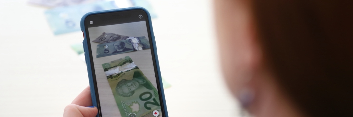 Money appears on the screen of an iPhone with the side of a woman's face in the foreground