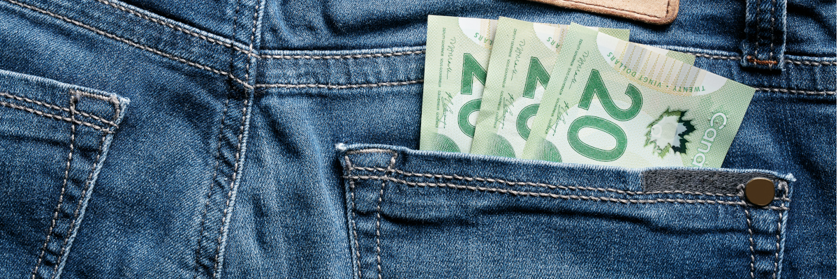 The backside of a pair of denim jeans. Three $20 bills are stuffed in the right hand pocket, 