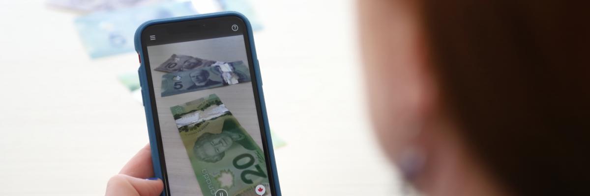 Money appears on the screen of an iPhone with the side of a woman's face in the foreground