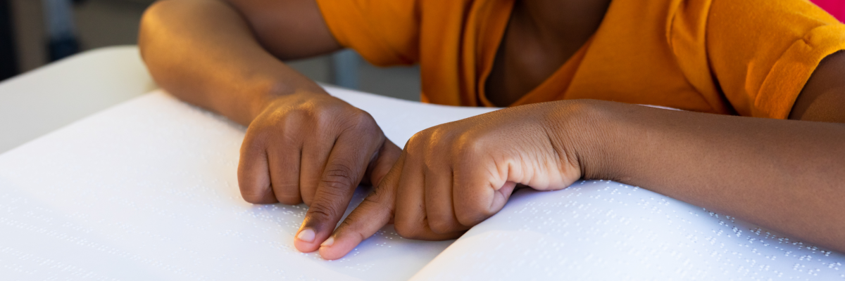 A young child reads a braille book. 