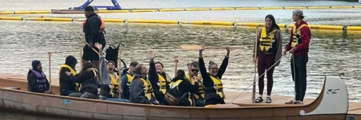 A group of 18 adult campers rowing a boat on the beautiful lake Joseph. 