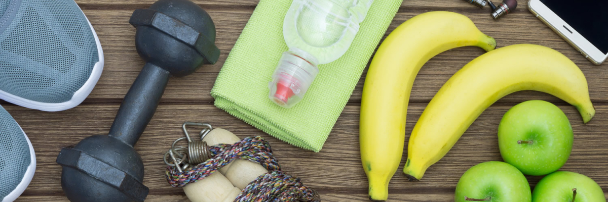 running shoes, dumbbell, fruit, and other health-related item are on a wood table.
