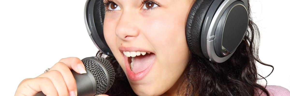 Young woman wearing headphones singing into a microphone