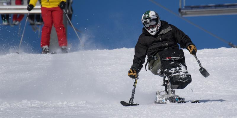 A para-alpine skier zooms down a snowy slope.