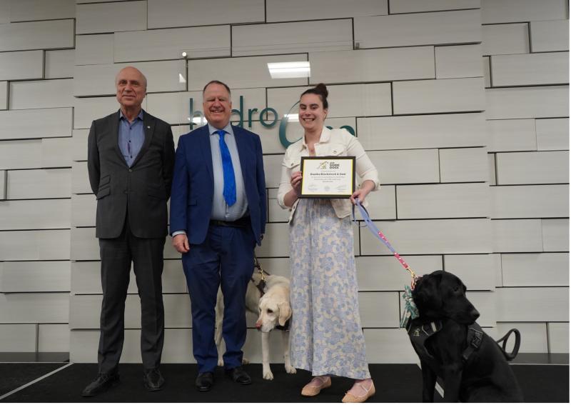 A guide dog handler and their black lab graduate together in an indoor setting
