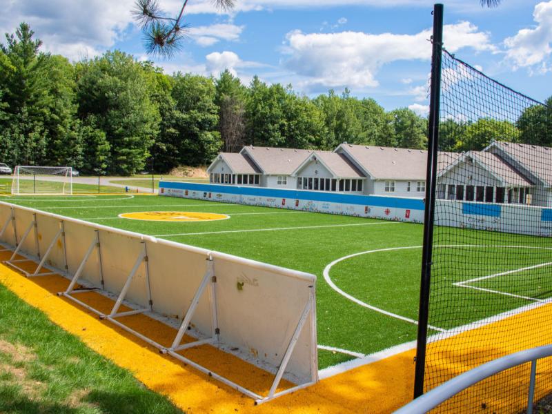 The accessible soccer pitch at CNIB Lake Joe, which features kickboards around the perimeter, textured borders made of walnut shell, and netting behind the goal.
