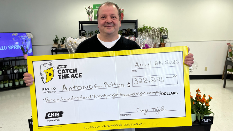 Antonio, a Catch the Ace jackpot winner, smiles and holds a giant signed cheque.