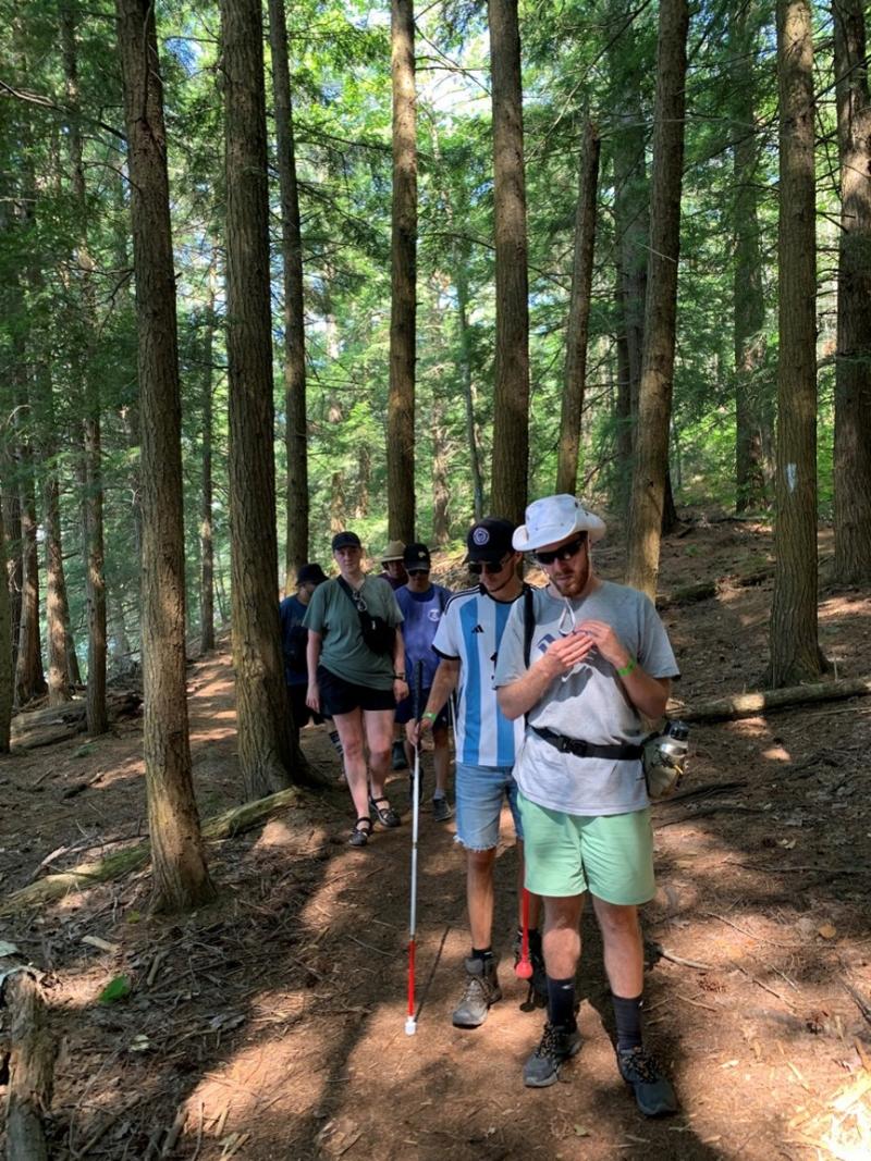 A group of campers walk along a forest trail.