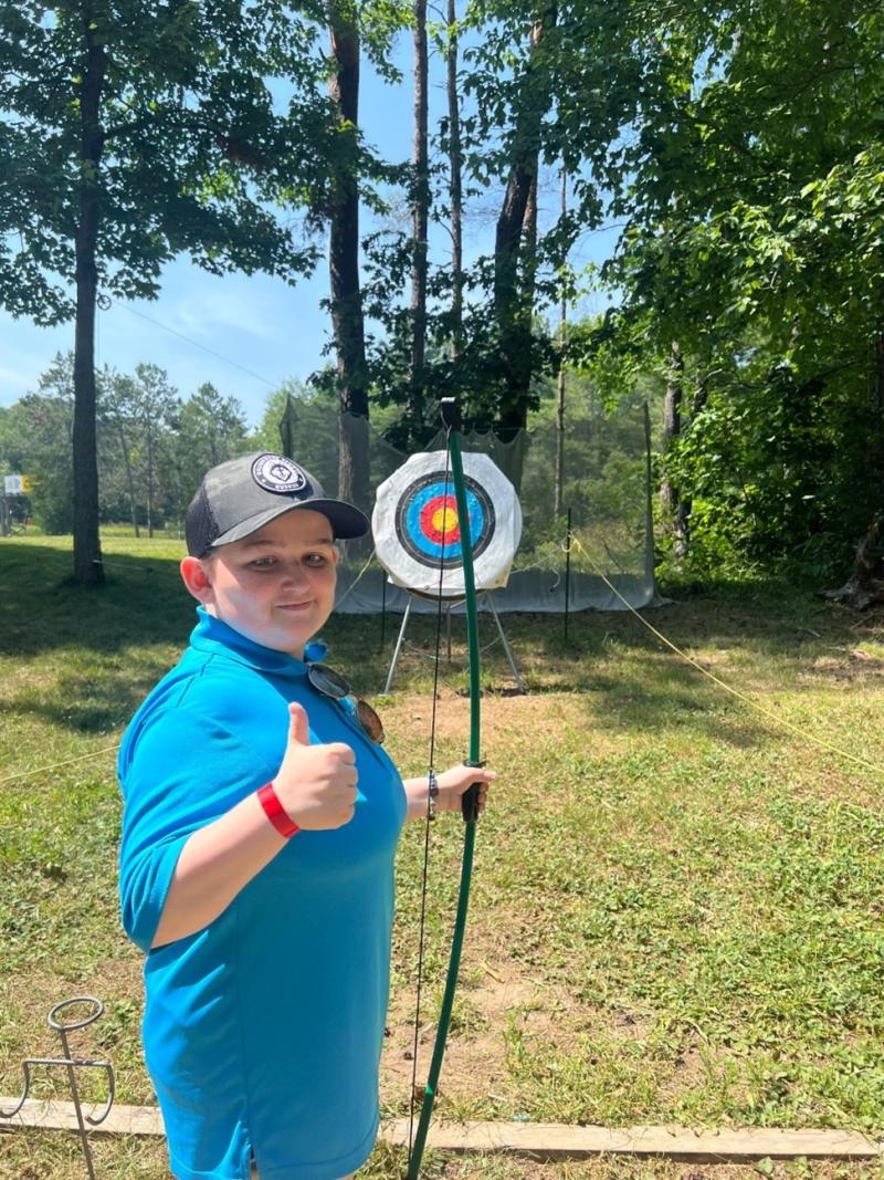 a young boy with his thumbs up smiling taking part in archery at lake joe