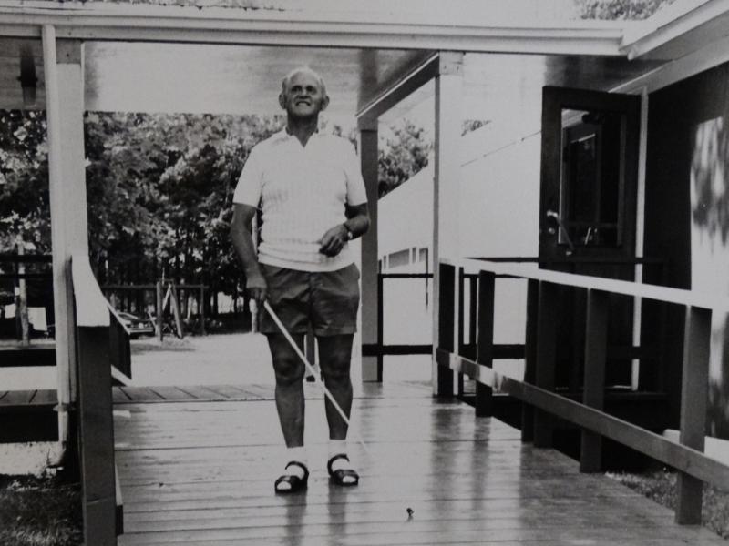 A black and white photo from the 1960s of a person using a white cane to navigate a walkway at CNIB Lake Joe.