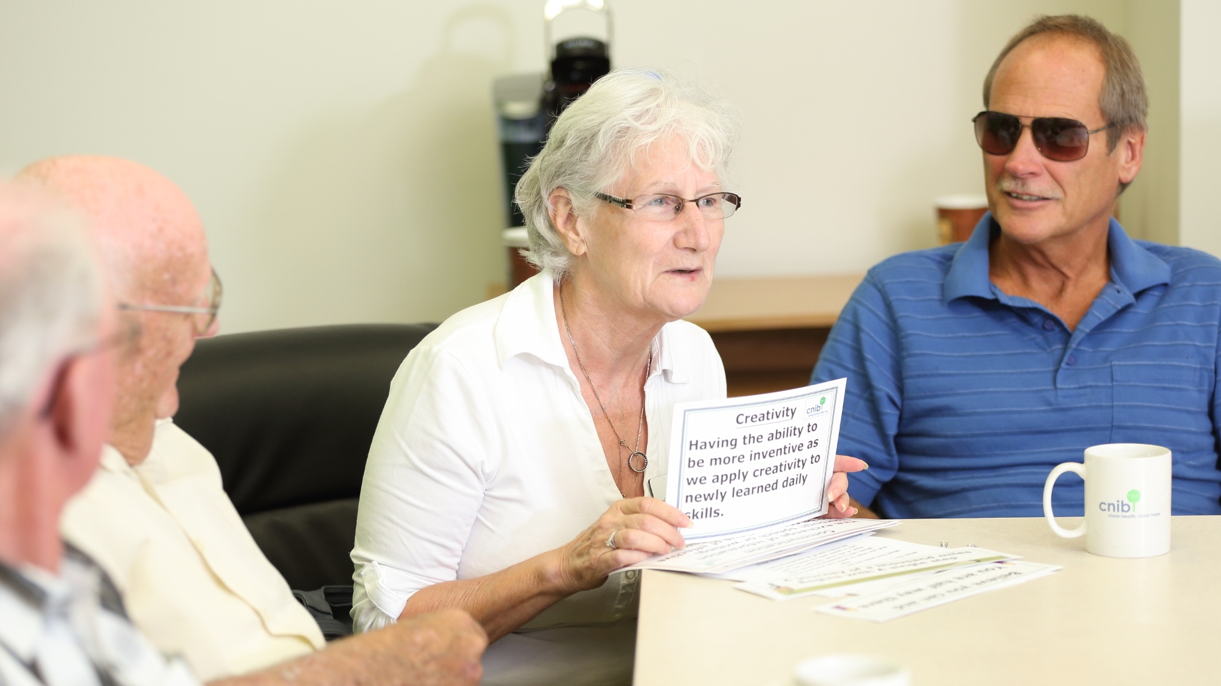 A peer support group. Four people engage in conversation around a table.
