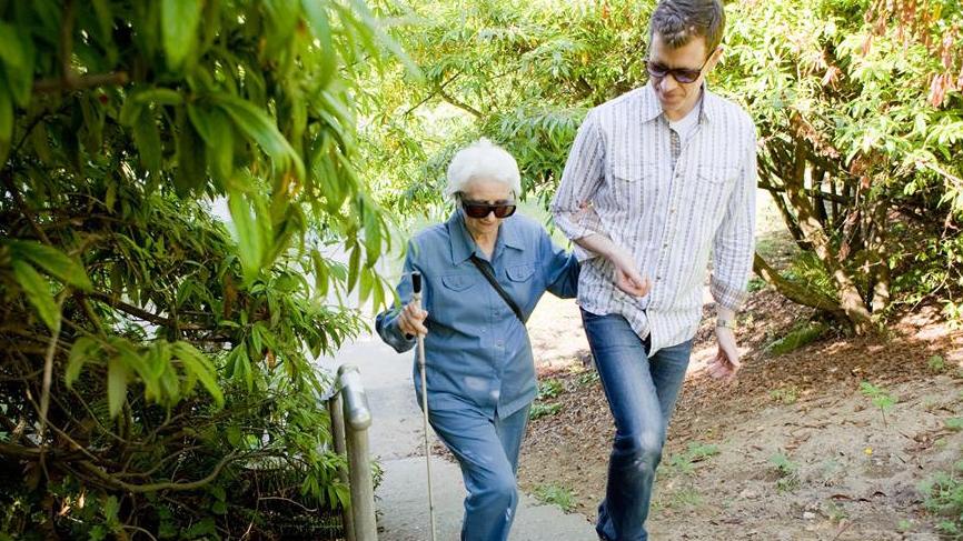 sighted guide walking with a woman using a white cane