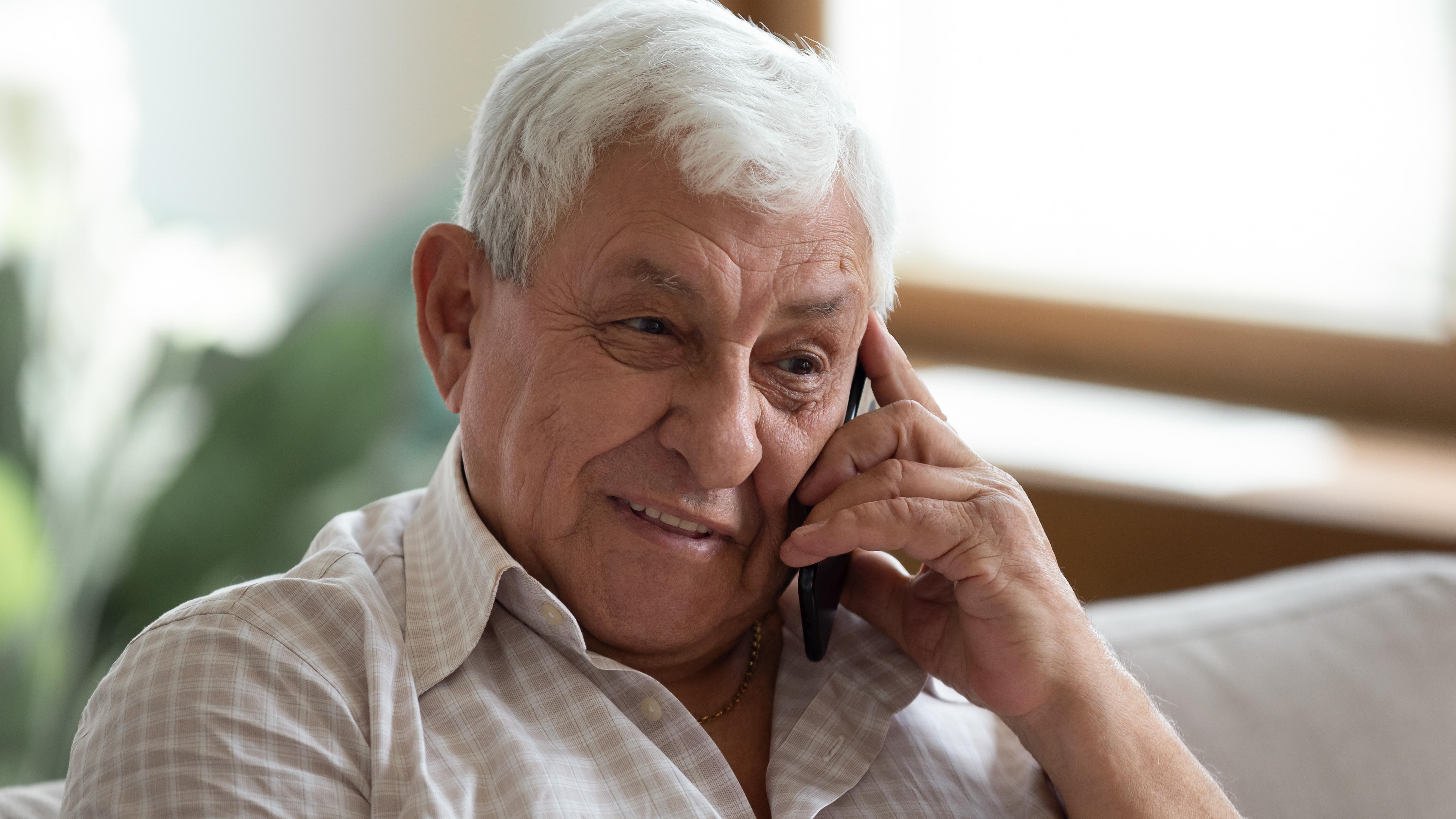 An elderly gentleman talks on a smartphone.