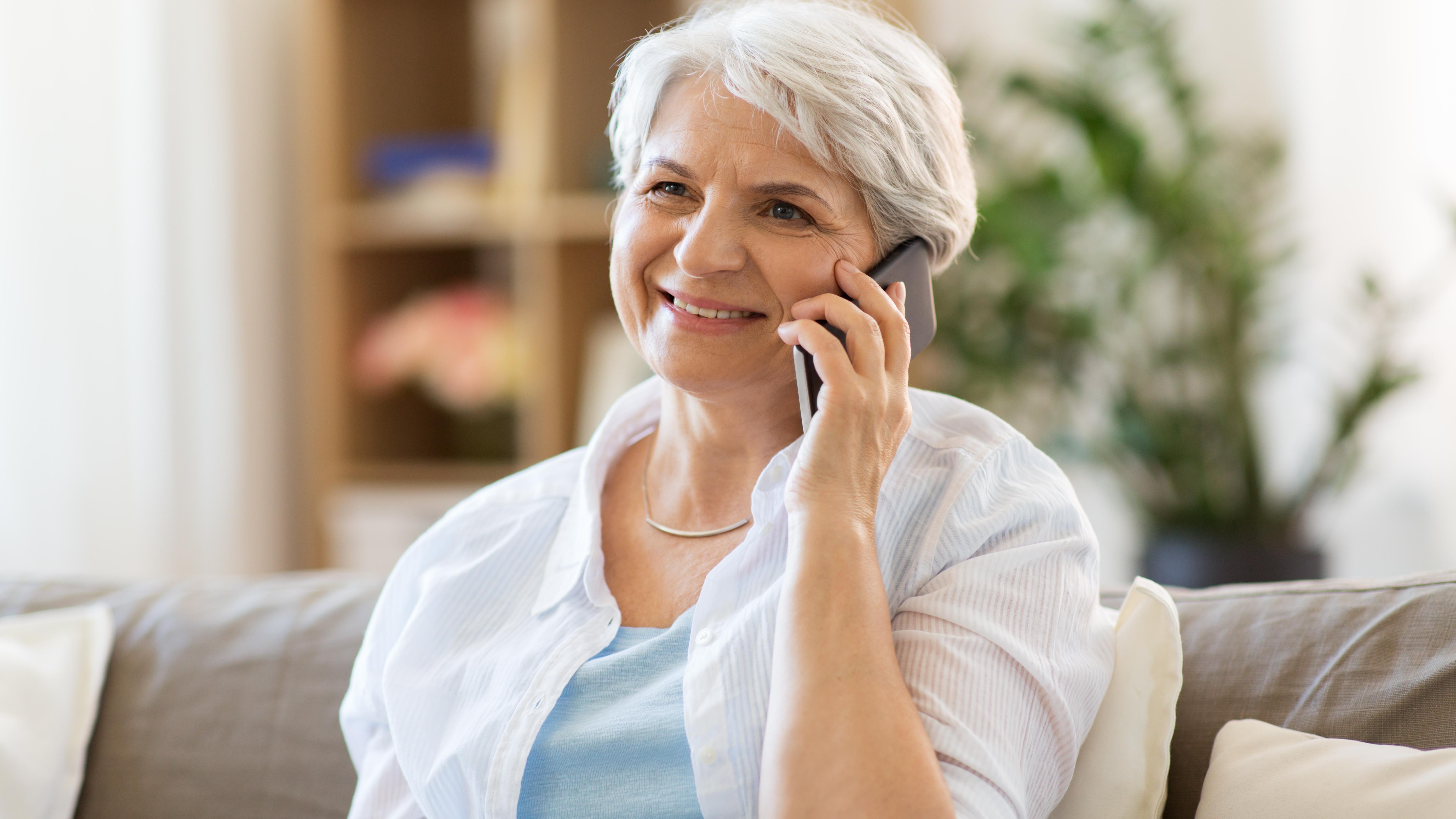 An elderly woman talks on a smartphone. 