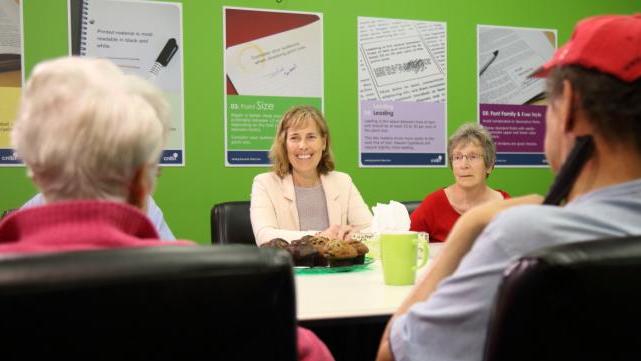 A group of four people sit at a table and engage in lively conversation. 