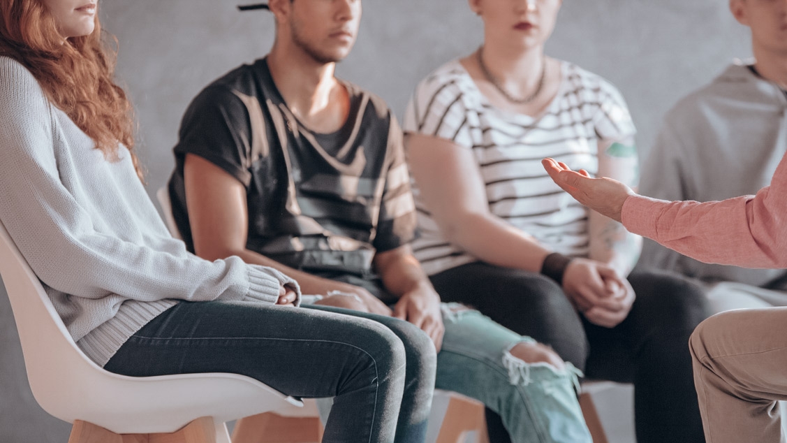 A group of five people sit in a circle and engage in lively conversation.