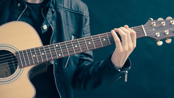 A man strums on a guitar. 