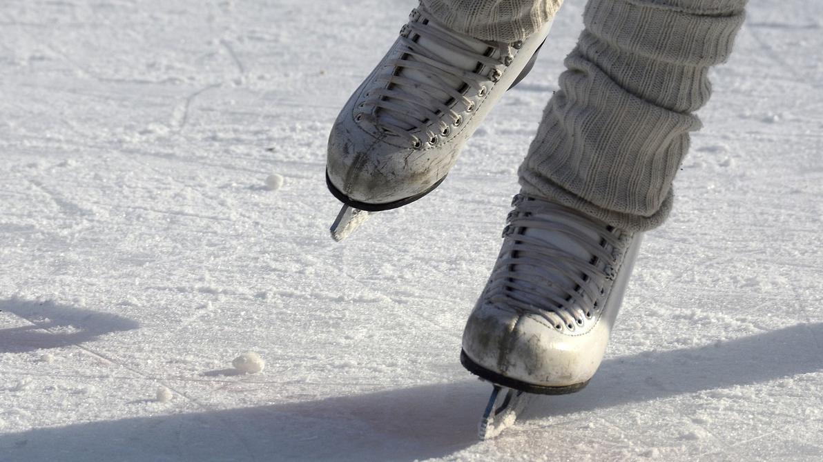 A pair of figure skates glide across an ice rink. 