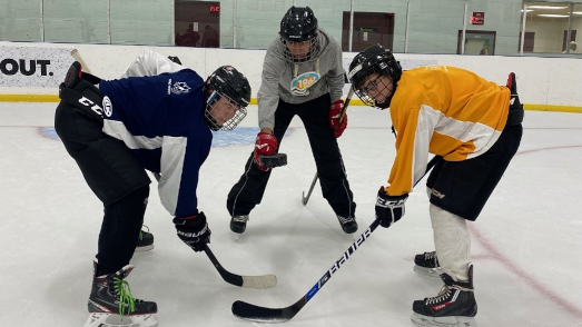 A puck drop. Hockey players, Brayden, Mathew and Eli during practice on the rink.