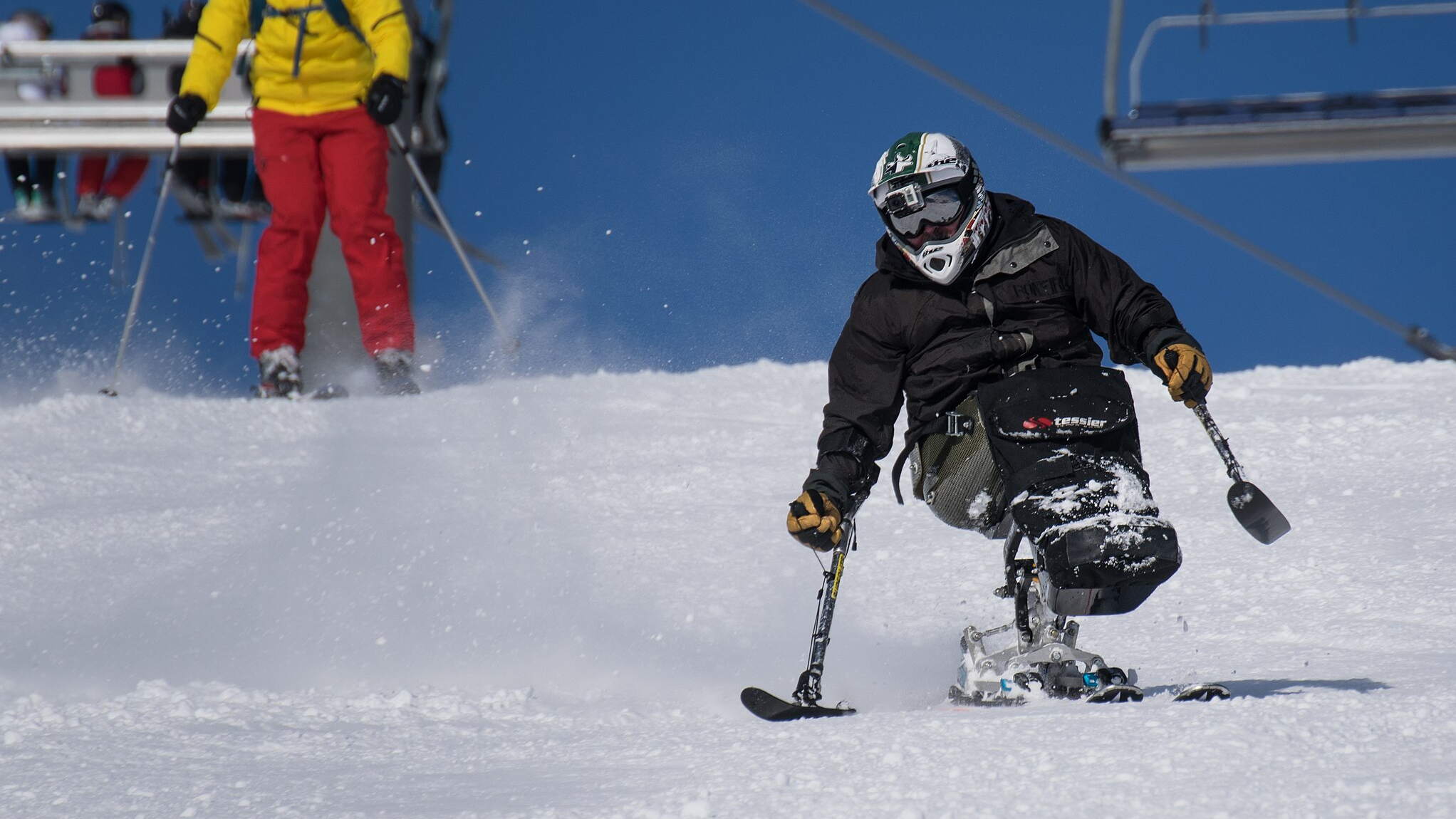 A para-alpine skier zooms down a snowy slope.