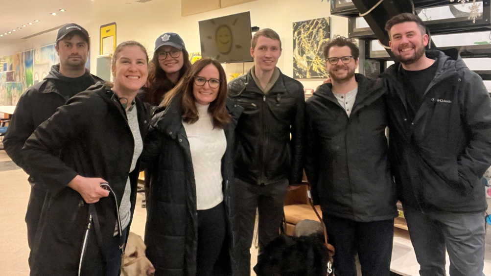 A group photo of Larissa and Shannon with four production crew members from the Ontario Police video and Jack, a handler featured in the video, at the GTA Community Hub. Larissa and Jack are accompanied by their guide dogs.