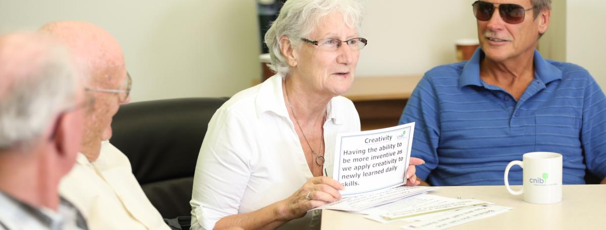 A peer support group. Four people engage in conversation around a table.