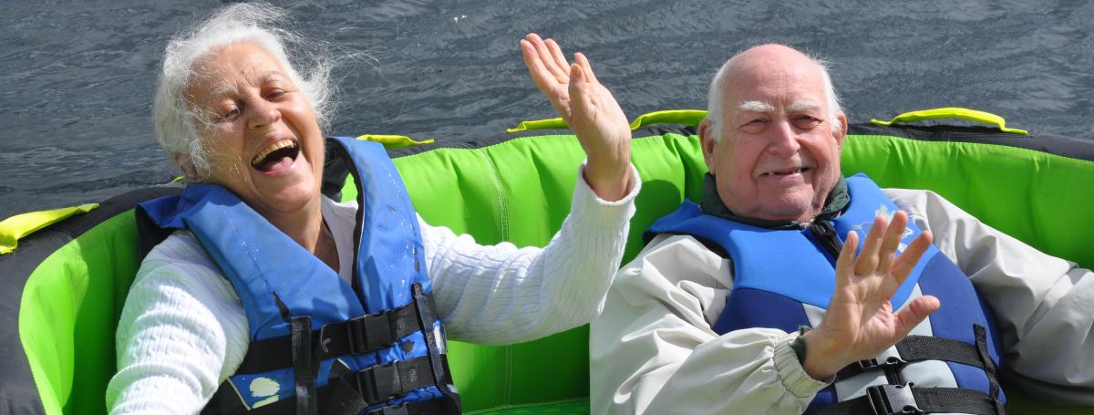 An older married couple laughing while water tubing