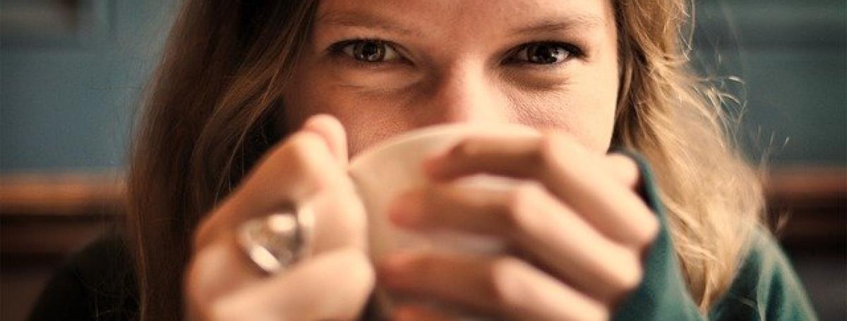 A woman sips on a cup of coffee.