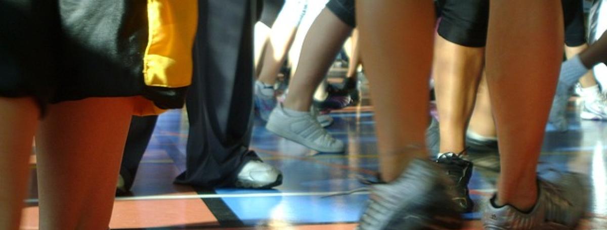 Feet move about during a dance class on a gymnasium floor.