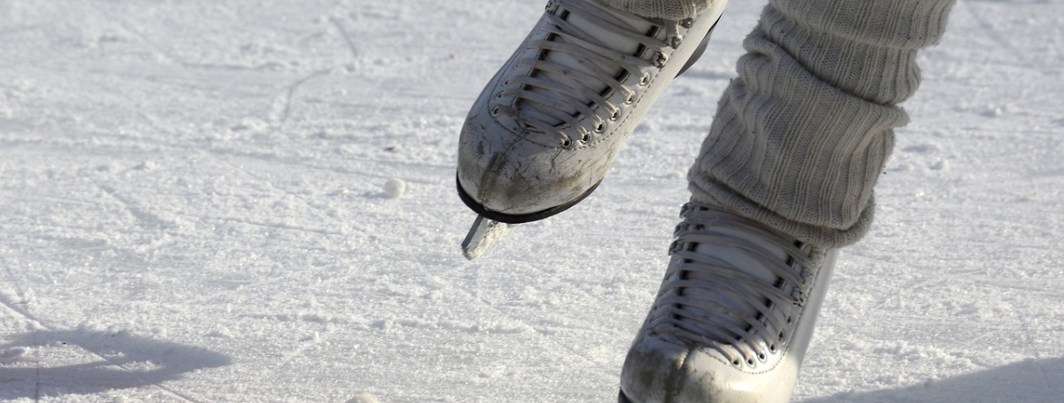 A pair of figure skates glide across an ice rink. 