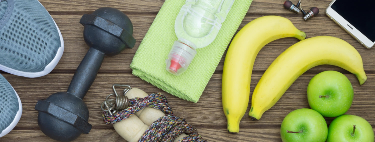 running shoes, dumbbell, fruit, and other health-related item are on a wood table.