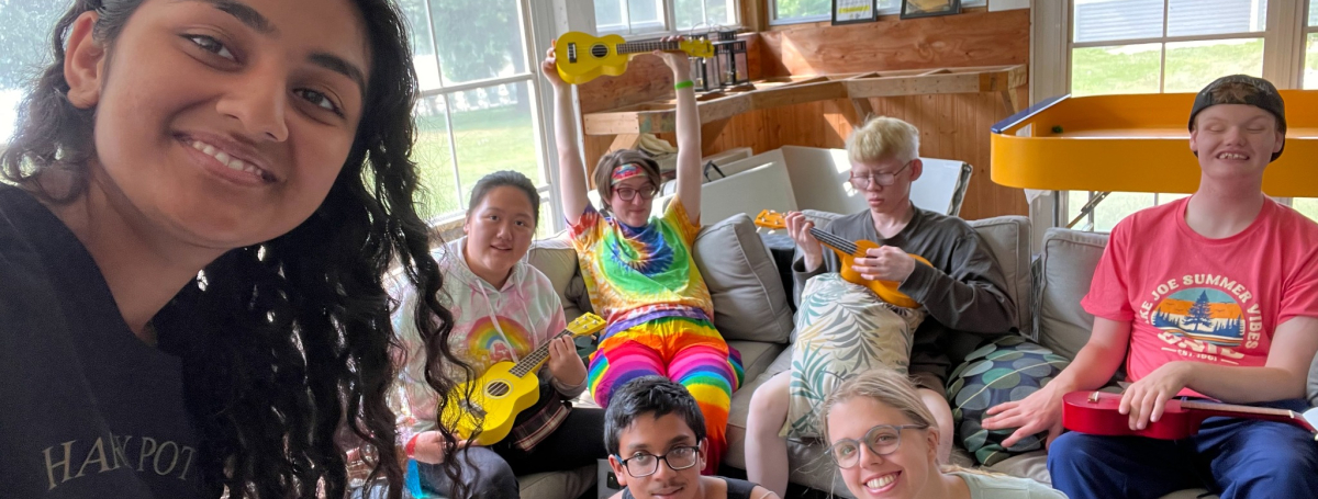 A female counsellor is standing in front of a group of participants playing ukeleles.
