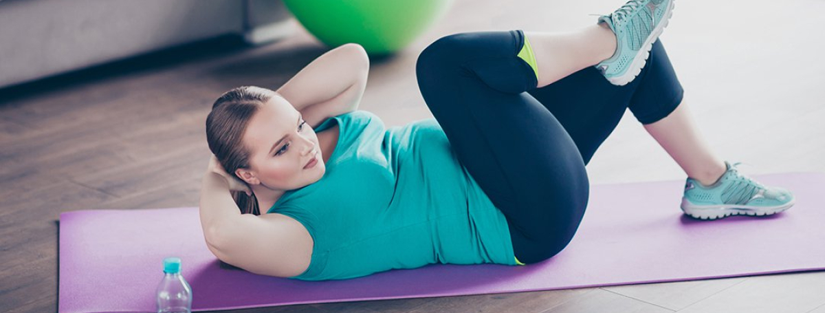 Woman exercising at home on a purple yoga mat. 
