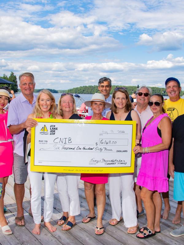 A group of people holding up a large cheque made out to CNIB