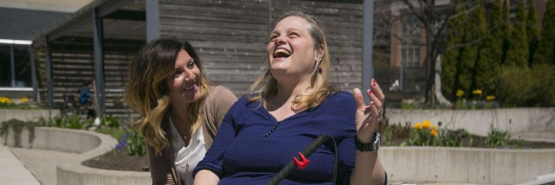 Two CNIB staff sit on the bench outside CNIB Bayview in Toronto. 