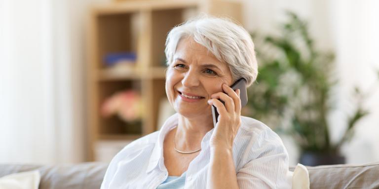 An elderly woman talks on a smartphone. 