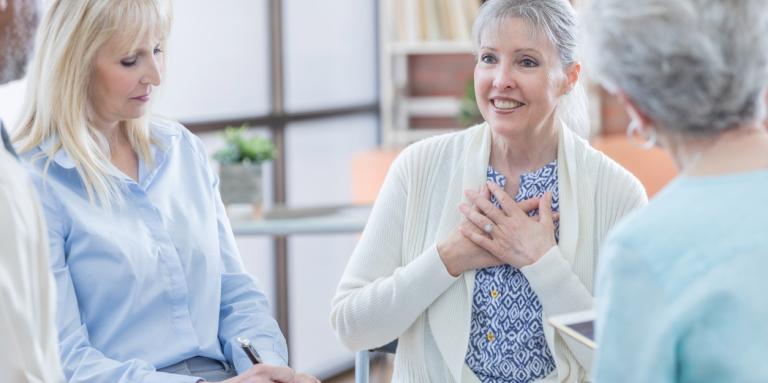 Three elderly women sit in a circle and engage in lively conversation. 