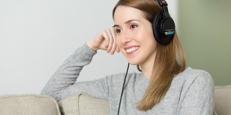 A young woman wears headphones and listens to music.