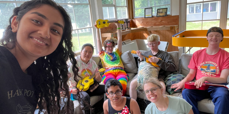 A female counsellor is standing in front of a group of participants playing ukeleles.