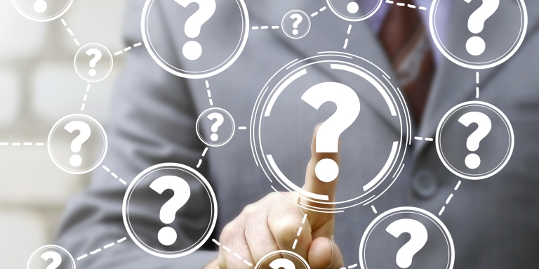 A finger points at a bunch of questions marks