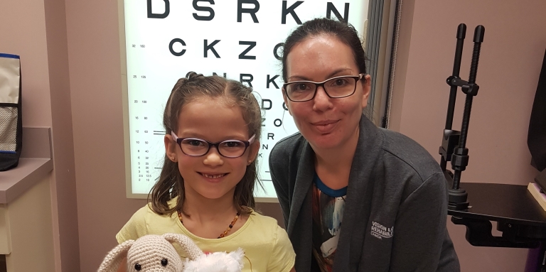 on the right, Teresa Aho, child and family services counsellor, on her left, Violet, holds Nash and her teddy bear, Fluffy. In the back ground is an eye chart.​