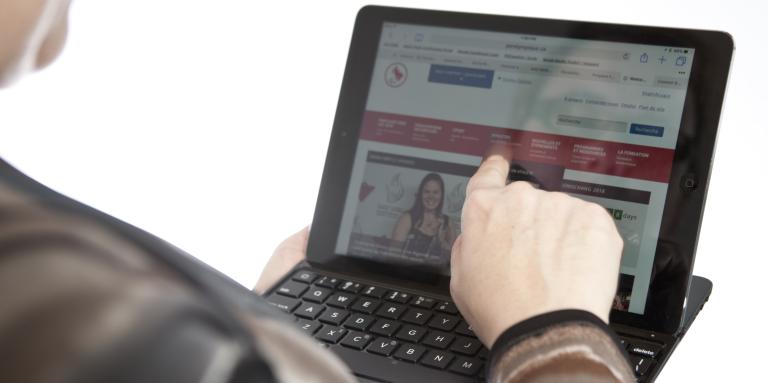 an over-the-shoulder shot of a client tapping an iPad. 