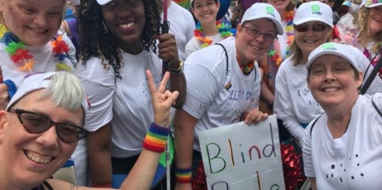 CNIB participants, staff and volunteers sporting white t-shirts and baseball caps in the Pride parade.