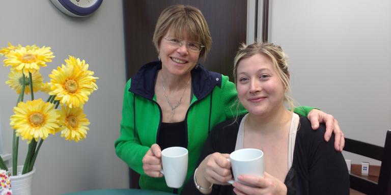 Two women holding coffee cups.