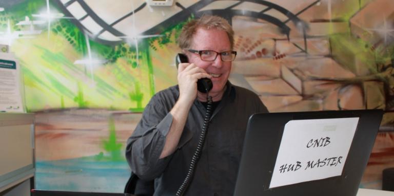 Michael using the phone at his desk at the Hub.